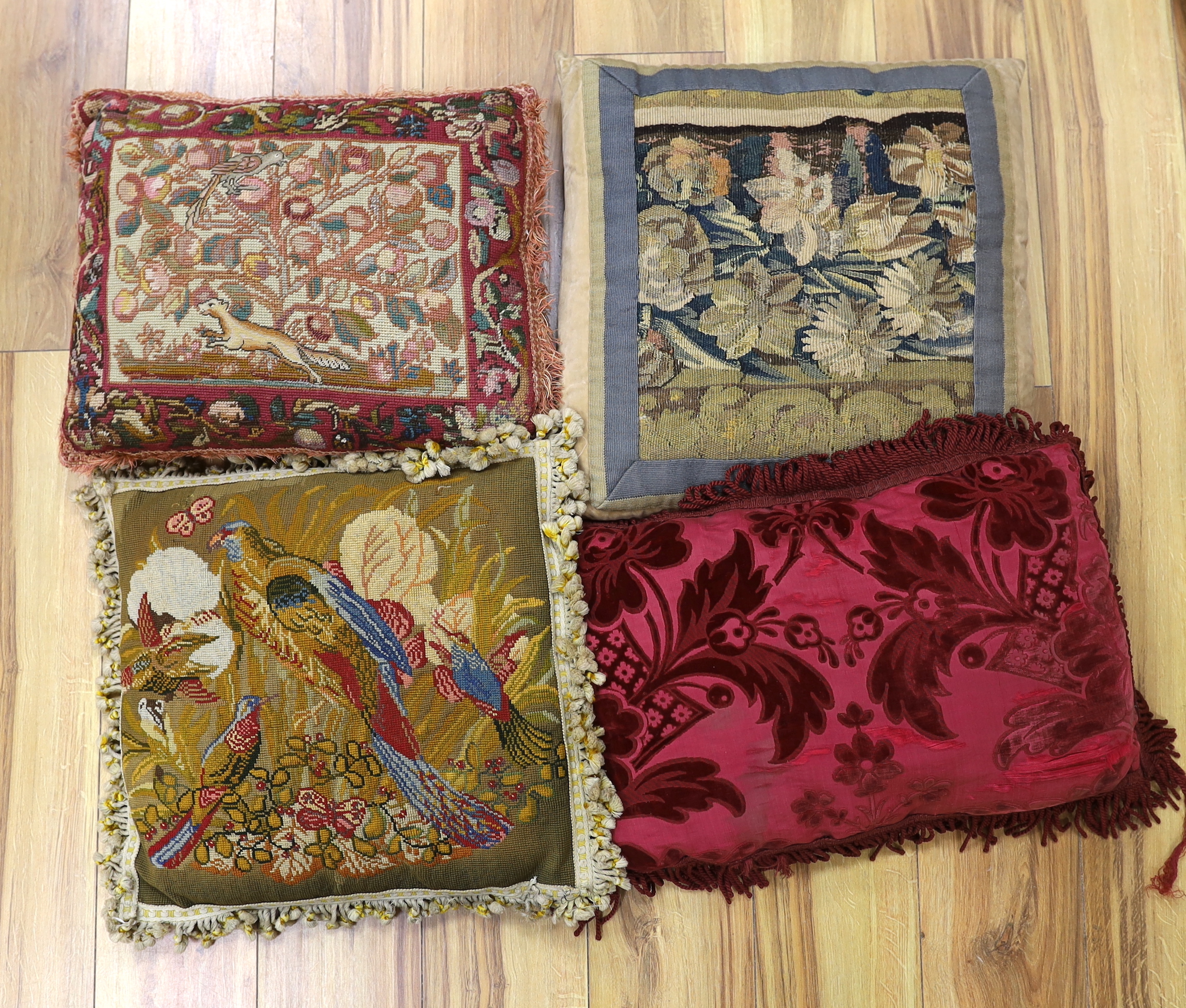 A late 18th century Flemish verdure tapestry fragment made into a cushion, a similar burgundy silk velvet damask cushion and two 19th early 20th century wool worked cushions (4)